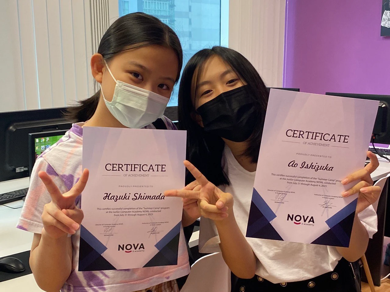 Two students proudly holding their NOVA certificates of achievement