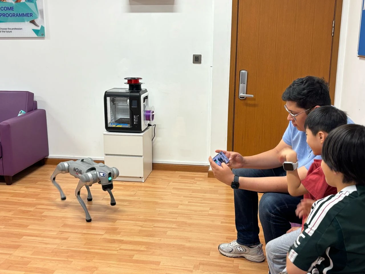 A NOVA robot dog demo watched by a parent and two children